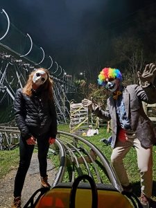 a creepy doll and a clown look at a rider in a mountain coaster cart